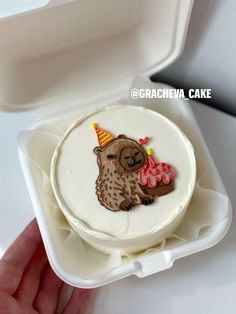 a small cake in a white box with a brown owl on it's face