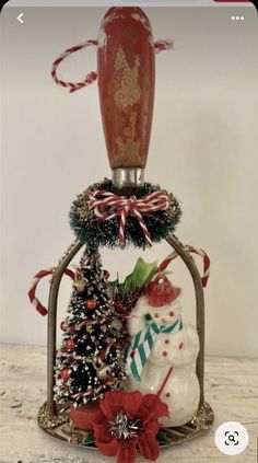 a snowman and christmas tree in a glass bell jar with red ribbon on top