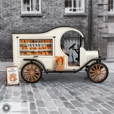 an old fashioned bakery cart is parked on the side of the road next to a brick building