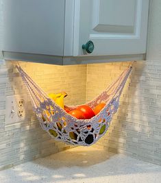 a hammock hanging from the side of a kitchen counter with fruit in it