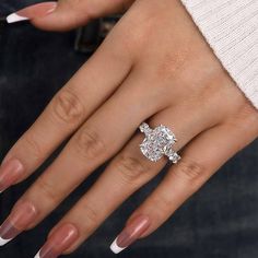 a woman's hand with a diamond ring on her finger and white nail polish