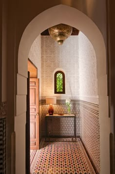 an archway leading to a bathroom with a tiled floor and walls, along with a potted plant on the counter