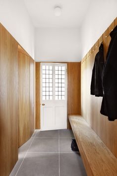 an empty hallway with wooden walls and coat racks