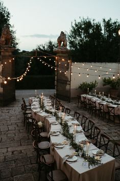 an outdoor dining table set up with candles and place settings for dinner guests to enjoy