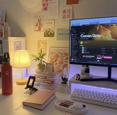 a desktop computer sitting on top of a white desk next to a lamp and other items