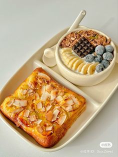 a white plate topped with two different types of food next to a bowl of fruit