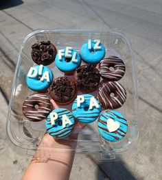 a plastic container filled with donuts covered in blue frosting and chocolate sprinkles