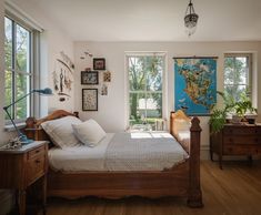 a bed sitting in a bedroom next to two windows with lots of light on them