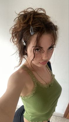 a woman in a green top is posing for the camera with her hair pulled back