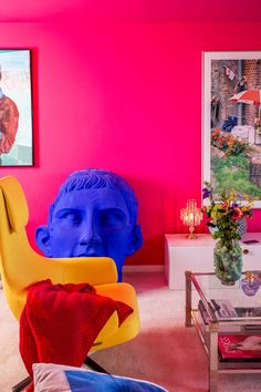 a living room filled with furniture and colorful art on the walls, including a large blue head