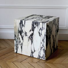 a white and black marble block sitting on top of a hard wood floor next to a wall