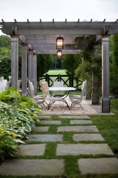 an outdoor dining area with stone walkway and pergolan style arbor, surrounded by lush greenery