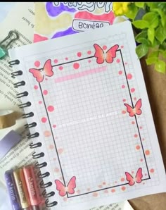 an open notebook with butterflies on it next to crayons, markers and pencils