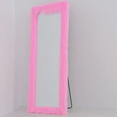 a pink mirror sitting on top of a white counter next to a black hair dryer