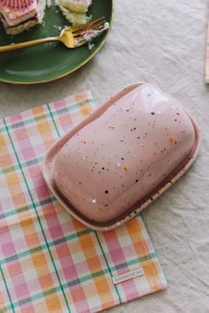 a plate with some cake on it sitting on a table next to a fork and napkin