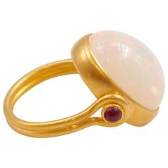 This antique style ring by Scrives is set with a large white opal cabochon of 10.68 cts with a strong play of colours including red, green, blue & yellow hues (unfortunately not so visible on the photos). The central stone and its setting are slightly turning in order to give more comfort. The band is composed of 2 gold strands surrounding two cabochons of ruby on the top part. Extra care and attention should be given to avoid damaging the opal (fragile stone). This one-of-a-kind ring is handmad Swivel Ring, Kinetic Jewelry, Yellow Gold Opal Ring, Antique Style Rings, Red Tourmaline, Yellow Hues, Opal Ring Gold, Gold Cocktail Ring, Contemporary Ring