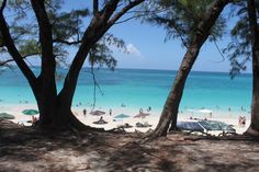 many people are on the beach with umbrellas and blue water in the back ground