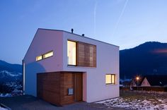 a modern house in the mountains at night with lights on and windows lite up