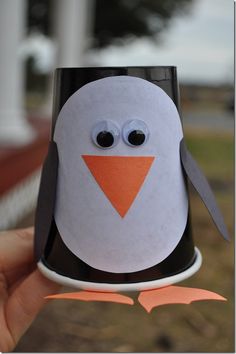 a hand holding up a paper cup with a penguin on it