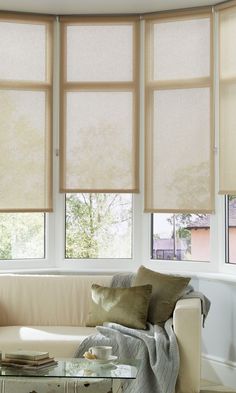 a living room filled with furniture and windows covered in roman blind shades on top of them