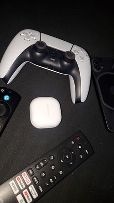 several remote controls are sitting next to each other on a black surface with two controllers