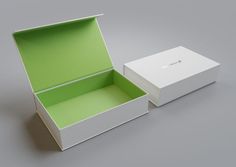 an open white box with a green lid and bottom is sitting on a gray surface