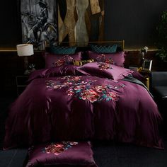 a bed with purple comforter and pillows in a dark room next to a painting on the wall