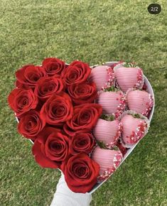 a bouquet of red roses and chocolates in a heart shaped box on the grass