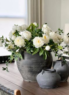 two vases with flowers in them sitting on a table