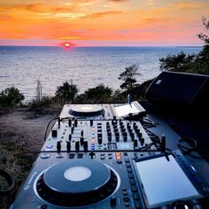 dj equipment sitting on top of a table next to the ocean at sunset or sunrise