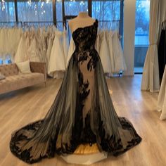 a black and white dress on display in a room with lots of dresses hanging from the windows