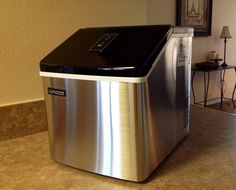 a metallic and black ice chest sitting on top of a counter next to a lamp