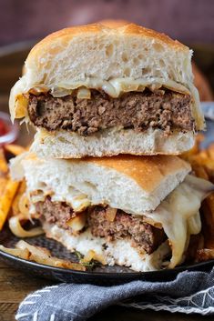 two cheeseburger sandwiches stacked on top of each other with fries in the background