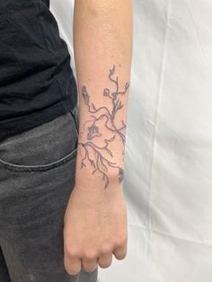 a woman's arm with a tattoo on it that has flowers and leaves growing out of it