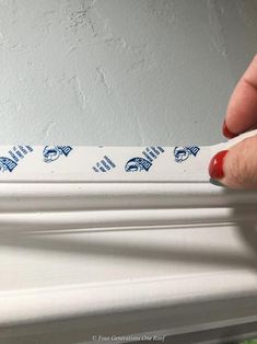 a person is marking the trim on a window sill with blue and white stickers