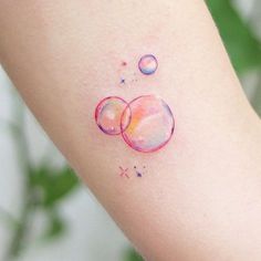 a woman's arm with watercolor bubbles on it and stars in the background