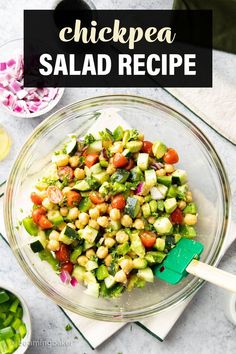 chickpea salad in a glass bowl with a green spatula on the side