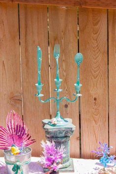 a table topped with blue candlesticks next to a vase filled with purple flowers