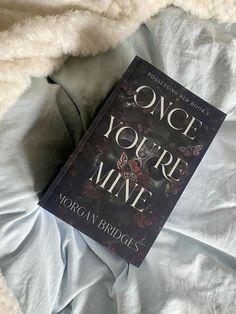 the book once you're mine is laying on top of a white bed sheet