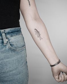 a woman's arm with a fish tattoo on the left side of her arm