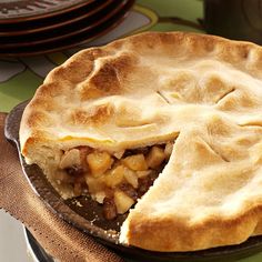 a pie sitting on top of a pan covered in food next to plates and utensils