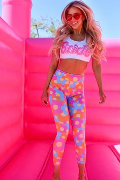 a woman standing on top of a pink inflatable slide