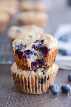 two blueberry muffins stacked on top of each other with fresh blueberries around them