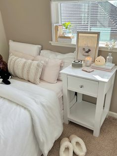 a white bed sitting next to a window covered in pillows and blankets on top of it