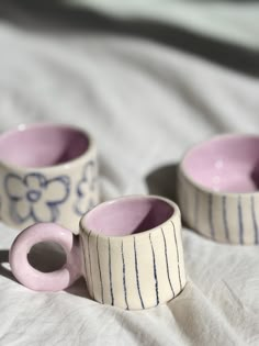 three ceramic cups sitting on top of a bed