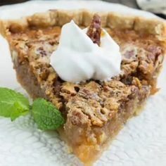 a piece of pie on a plate with whipped cream and mint sprig garnish