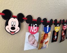 a mickey mouse birthday banner hanging on the wall with photos and magnets attached to it