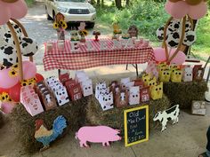 a table topped with lots of farm animals next to hay bales covered in pink and yellow decorations