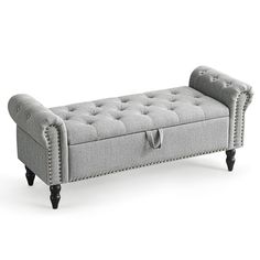 a gray bench with studded legs and buttons on the back, in front of a white background