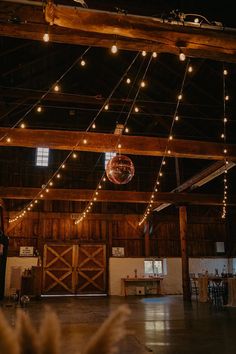 the inside of a barn with lights strung from the ceiling